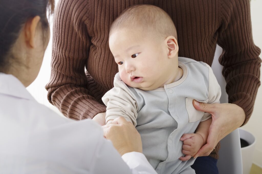医師の前で抱っこされる赤ちゃん