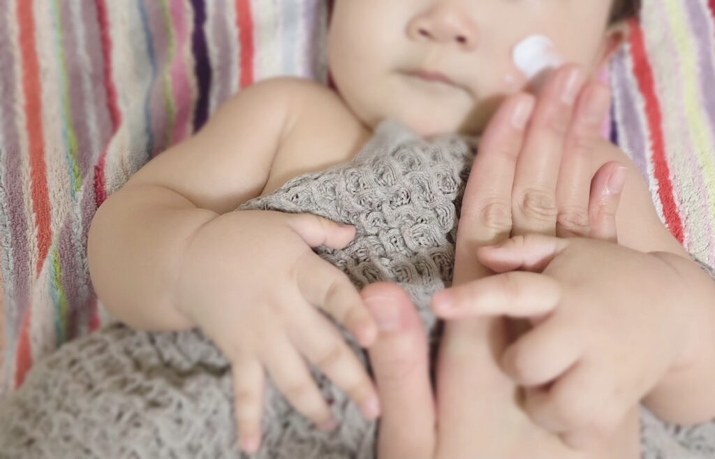 赤ちゃんの肌に保湿クリームを塗る様子