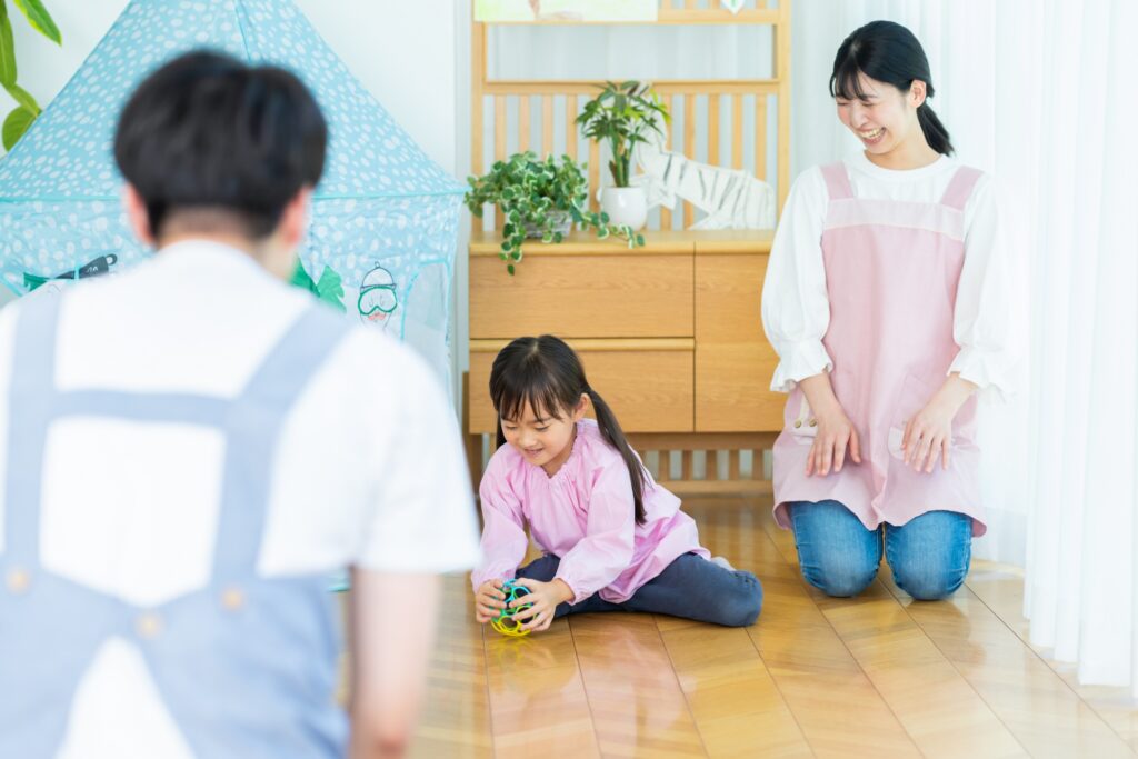 明るい保育室で過ごす子どもと保育士