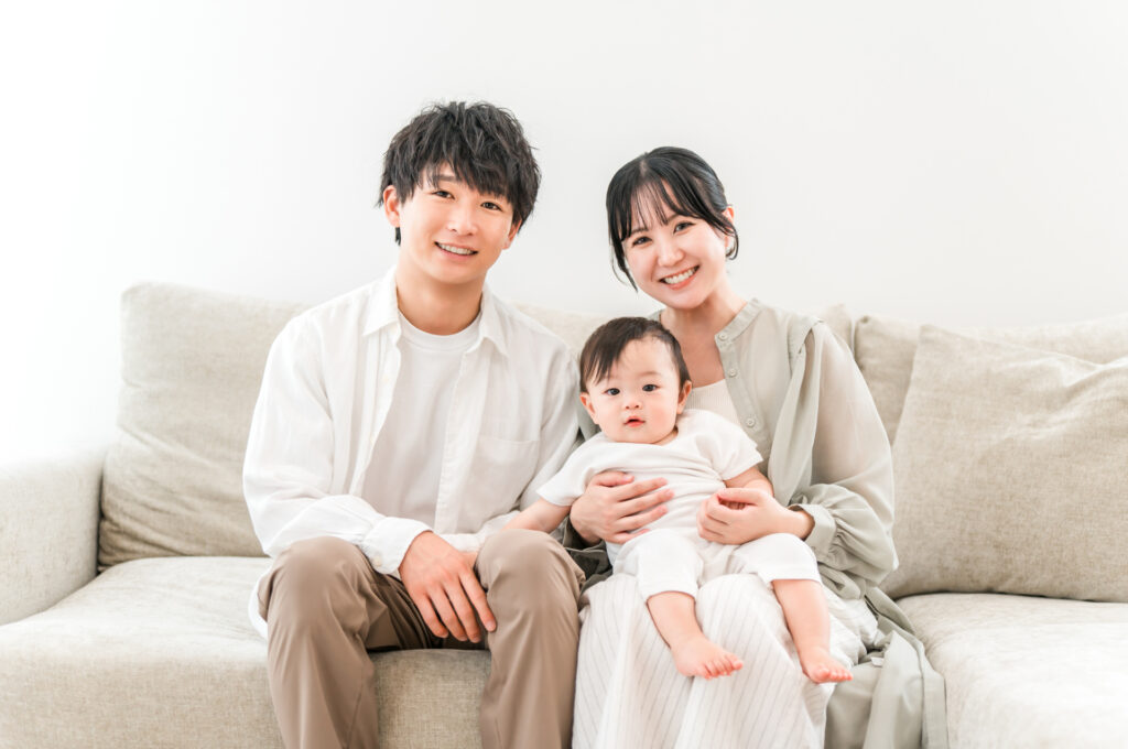 ソファに座って赤ちゃんを抱っこする夫婦