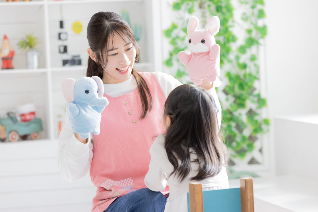 保育園でおもちゃを使って遊ぶ子どもと保育士